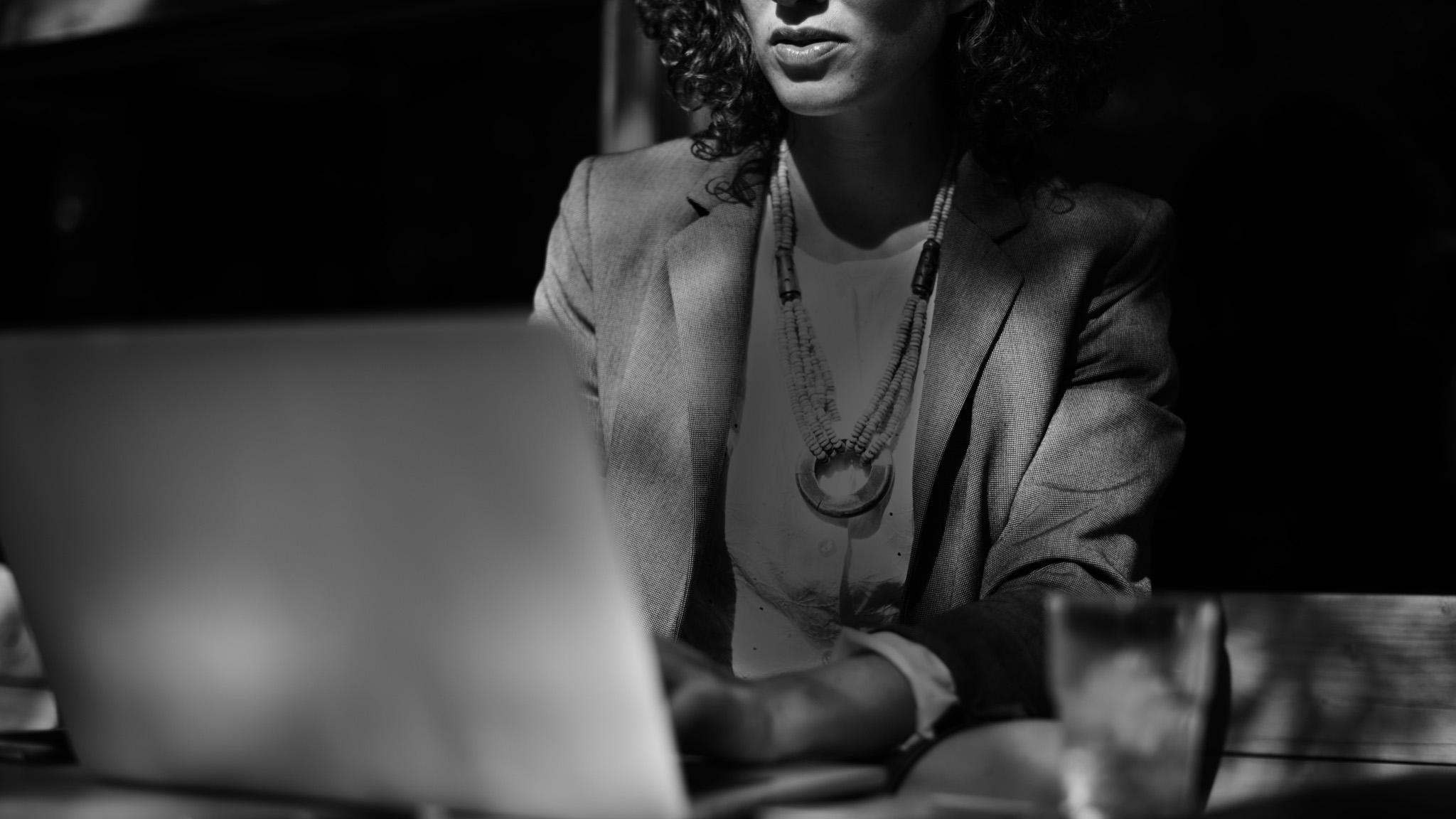 A woman types at a computer wearing business casual attire.